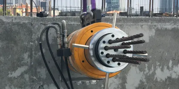 Multi-strand pre-stressing jack anchored to a concrete wall on a construction site